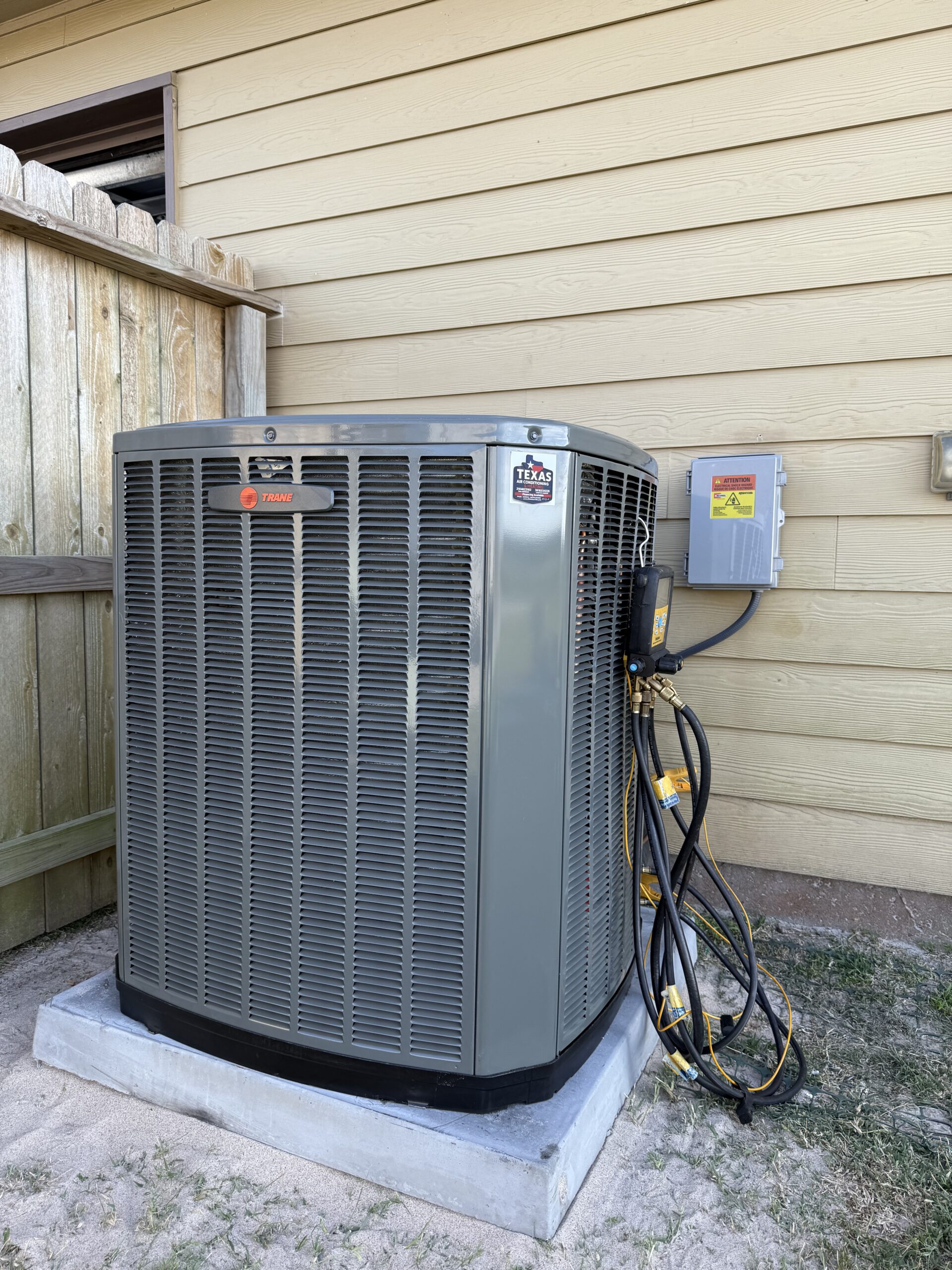Technician servicing outdoor AC condenser in San Antonio backyard