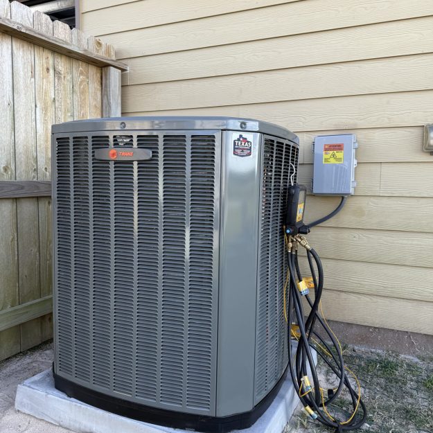 Technician servicing outdoor AC condenser in San Antonio backyard